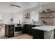 Modern kitchen featuring dark cabinets, stainless steel appliances, an island with seating, and floating shelves at 3400 Moore St, Wheat Ridge, CO 80033