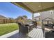 Covered back porch featuring outdoor seating and a view of the fenced backyard and lush lawn at 16308 Saint Paul St, Thornton, CO 80602