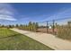 A community tennis court behind a fence with green lawn and trees at 16308 Saint Paul St, Thornton, CO 80602