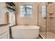 Bright bathroom showcasing soaking tub, tiled shower, and window with blinds at 2134 S Poppy St, Lakewood, CO 80228