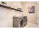 Modern laundry room with white shiplap, wood shelves, and gray LG washer and dryer at 2134 S Poppy St, Lakewood, CO 80228