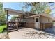Exterior view of the home featuring a covered deck with wooden steps, a concrete patio, and a partially brick facade at 5898 Parfet Ct, Arvada, CO 80004