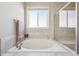Relaxing bathroom featuring a large soaking tub, tiled surround, and a window providing natural light at 15993 E 112 Pl, Commerce City, CO 80022