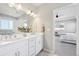 Well-lit bathroom featuring double sinks, white cabinets, and a mirror offering a view into the main bedroom at 15993 E 112 Pl, Commerce City, CO 80022