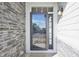 Close-up of the front door, featuring a screen door, stylish sconce, and stone and plank accents at 15993 E 112 Pl, Commerce City, CO 80022
