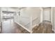 Hallway with wood floors, white banister, access to living areas, and a door, painted in neutral tones at 15993 E 112 Pl, Commerce City, CO 80022
