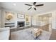 Bright living room with a gray fireplace, built-in shelving, ceiling fan, and hardwood floors with light-colored area rug at 15993 E 112 Pl, Commerce City, CO 80022