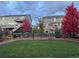 Landscaped backyard with green grass, rock features, and vibrant autumn foliage, complementing the home's exterior at 26960 E Costilla Dr, Aurora, CO 80016