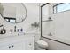Modern bathroom features a sleek vanity, round mirror, and a glass-enclosed shower/tub combination at 1567 Arrowpoint Ct, Franktown, CO 80116