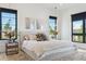 Bright bedroom boasts large windows, modern decor, and plush, neutral-toned bedding and side tables with floral decor at 1567 Arrowpoint Ct, Franktown, CO 80116