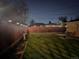 The backyard features a well-manicured lawn and a wood privacy fence with lighting at night at 2488 S Zurich Ct, Denver, CO 80219