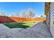 View of backyard with stone patio, lush lawn, mature trees, and privacy fence at 2488 S Zurich Ct, Denver, CO 80219