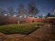 A well-manicured backyard features a patio and wood privacy fence with lighting in the evening at 2488 S Zurich Ct, Denver, CO 80219