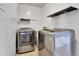 Bright laundry room area featuring a modern washer and dryer with shelving at 2488 S Zurich Ct, Denver, CO 80219