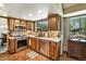 Well-lit kitchen featuring stainless steel appliances, warm wood cabinetry, and tiled countertops at 8065 W Fremont Dr, Littleton, CO 80128