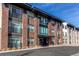 Modern brick apartment building with large windows and black trim under a blue sky at 155 S Monaco Street Pkwy # 311, Denver, CO 80224