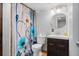 Bathroom features a vanity with a dark wood cabinet, a toilet, and a patterned shower curtain at 5611 S Sicily Cir, Aurora, CO 80015