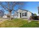 Well-maintained home with lush lawn, mature tree, and a two-car attached garage, set against a clear blue sky at 5611 S Sicily Cir, Aurora, CO 80015