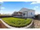 Back exterior of the home with a well-maintained lawn, patio area, and charming architectural details at 5611 S Sicily Cir, Aurora, CO 80015