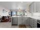 Modern kitchen with gray cabinets, stainless steel appliances, and an open view to the living room at 5611 S Sicily Cir, Aurora, CO 80015