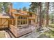 Expansive rear exterior featuring a multi-tiered deck, lush greenery and a Tudor style home at 70 Long Bow Cir, Monument, CO 80132