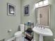 Charming bathroom with a pedestal sink, framed artwork, and toilet with shelving at 4704 W Hinsdale Ct, Littleton, CO 80128