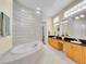 Bright bathroom with a jetted tub, glass block wall, and double vanity sinks at 4704 W Hinsdale Ct, Littleton, CO 80128
