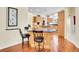 Bright kitchen with wood cabinetry, a dark countertop island with seating, and hardwood flooring at 4704 W Hinsdale Ct, Littleton, CO 80128