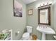 Stylish powder room with a pedestal sink, decorative mirror, and soft green walls for a refreshing feel at 4704 W Hinsdale Ct, Littleton, CO 80128