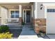 Inviting front porch with brick accents, a cozy sitting area, a wreath on the front door, and manicured landscaping at 15131 Munich Ave, Parker, CO 80134