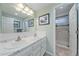 Bright bathroom boasts a double sink vanity, framed mirror, and a shower with glass doors at 8116 W Fremont Dr, Littleton, CO 80128