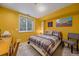 Bright bedroom with yellow walls features a comfortable bed, side table and basement egress window at 8116 W Fremont Dr, Littleton, CO 80128