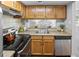 Functional kitchen with stainless steel dishwasher, wood cabinets, and view to living area at 1250 S Monaco Pkwy # 50, Denver, CO 80224