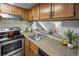 Functional kitchen with stainless steel appliances, wood cabinets, and view to living area at 1250 S Monaco Pkwy # 50, Denver, CO 80224