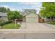 Charming home with a green exterior, brick accents, and a large, two-car garage at 2427 Cherry Cir, Brighton, CO 80601