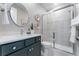 Modern bathroom with a gray vanity, round mirror, and glass-enclosed shower at 4334 Ridgewalk Pt, Castle Rock, CO 80108