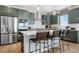 Kitchen island with counter seating and stainless steel appliances with dark green cabinetry at 4334 Ridgewalk Pt, Castle Rock, CO 80108