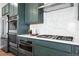 Close up of gas stove and stainless steel oven and green kitchen cabinetry at 4334 Ridgewalk Pt, Castle Rock, CO 80108