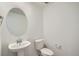 Well-lit powder room with a pedestal sink, oval mirror, and toilet with all white coloring at 14578 W 90Th Ln # B, Arvada, CO 80005