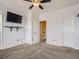 Bright bedroom featuring a ceiling fan, neutral carpet, and a mounted TV with floating shelf at 11250 Florence St # 20B, Commerce City, CO 80640