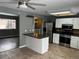 Bright eat-in kitchen features stainless appliances, white cabinetry, tile backsplash, and adjacent living area at 20328 E Powers Ln, Aurora, CO 80015