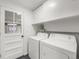 Functional laundry room with white appliances and storage shelves at 8793 E Monmouth Pl, Denver, CO 80237