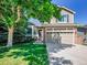 Charming two-story house with lush green lawn, mature trees, and a two-car garage at 1234 Riddlewood Ln, Highlands Ranch, CO 80129