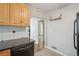 Kitchen showcasing sleek countertops, wood cabinets, black appliances, and access to other rooms at 4072 Ames St, Wheat Ridge, CO 80212