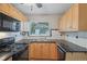 Well-lit kitchen featuring wood cabinets, black appliances, tile countertops, and a double sink at 4072 Ames St, Wheat Ridge, CO 80212