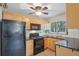 Kitchen featuring wood cabinets, black appliances, tile countertops, and a window at 4072 Ames St, Wheat Ridge, CO 80212