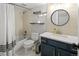 Well-lit bathroom featuring a shower-tub combo, blue vanity, and decorative round mirror at 1777 Spruce St, Denver, CO 80220