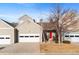 Townhome exterior featuring a two-car garage, red front door, and tidy landscaping at 15555 E 40Th Ave # 6, Denver, CO 80239