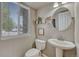 Charming half bathroom featuring a pedestal sink, toilet, decorative accents, and natural light from the window at 12646 S Dove Creek Way, Parker, CO 80134