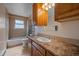 Well-lit bathroom with tile floors, a full bathtub, and wooden cabinets at 8690 E Chenango Ave, Denver, CO 80237
